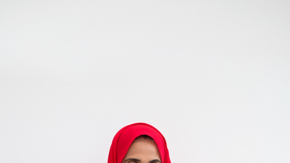 Woman in a red hijab standing behind a table of ingredients